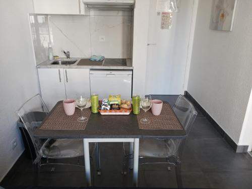una pequeña cocina con una mesa con vasos y comida. en studio à 2 mn à pied de la plage en Niza