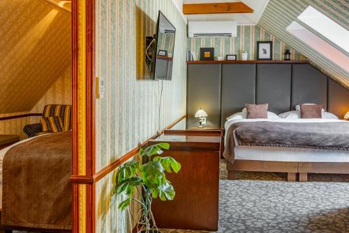 Un dormitorio con una cama y una mesa con una planta en Hotel Golden Eagle, en Levice