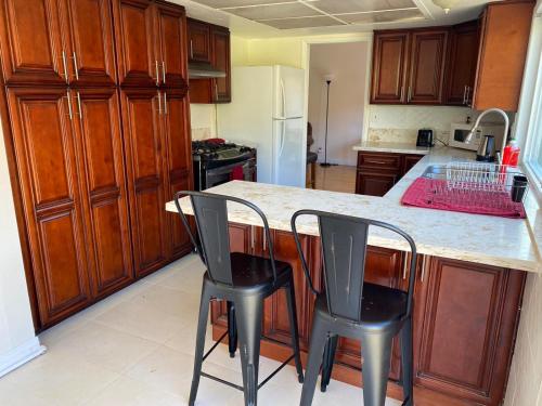 una cocina con armarios de madera y una encimera con 2 sillas en Zen Home, en Santa Ana