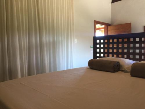 a bedroom with a bed and a window with curtains at Chalé Bromélia do Cerrado in Serra do Cipo