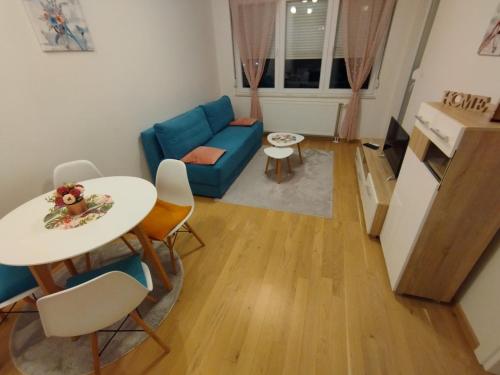 ein Wohnzimmer mit einem blauen Sofa und einem Tisch in der Unterkunft Ada apartman in Banja Luka