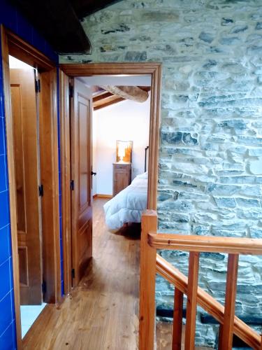 a stone wall in a bedroom with a bed at Casa Pacios by M de Santiago in Tríacastela