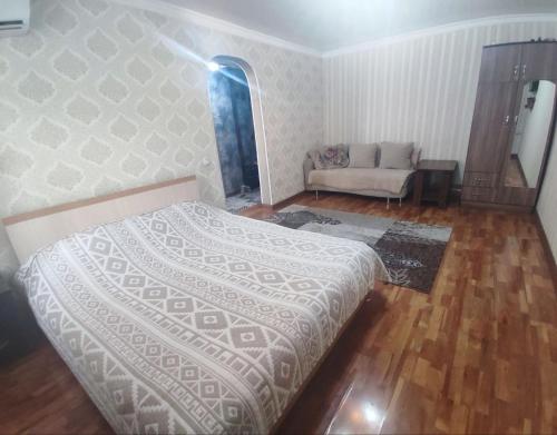 a bedroom with a bed and a couch in it at Комфортная квартира для 2х персон in Bishkek
