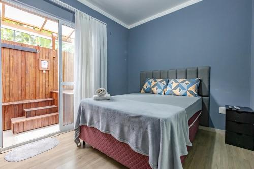 a bedroom with a bed with blue walls and a window at Apartamento 2 quartos com Spá Expocentro Praias in Balneário Camboriú