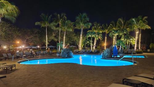 ein Pool mit Palmen und Liegestühlen bei Nacht in der Unterkunft Lely Resort Naples Golf Villa, Free Golf, Heated Pool, Pickleball & Tennis in Naples