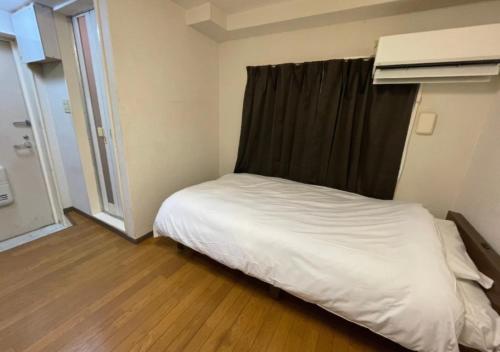 Un pequeño dormitorio con una cama con sábanas blancas y una ventana en Beverly Homes Osaki Room 203, Room 205, Room 301, - Vacation STAY 89071v, en Tokio
