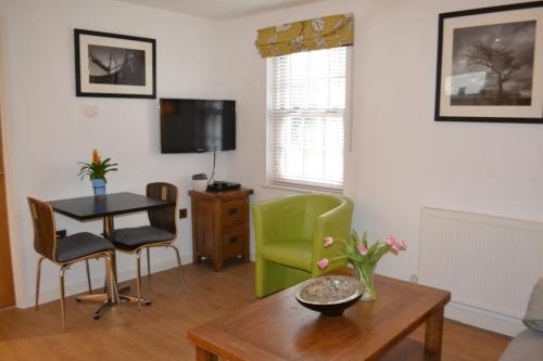 a living room with a table and a green chair at Entire apartments in the heart of the Suffolks - GL50 Apartments in Cheltenham