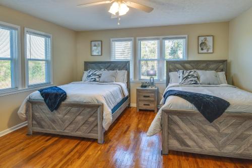 two beds in a bedroom with wood floors and windows at Tuskegee Countryside Retreat on 7 Acres! in Tuskegee