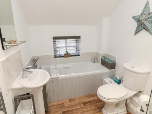 a bathroom with a tub and a toilet and a sink at Lavenna in Alnwick