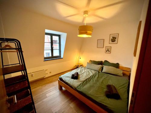 Schlafzimmer mit einem Bett mit grüner Bettwäsche und einem Fenster in der Unterkunft Altstadt Lounge Pirna in Pirna