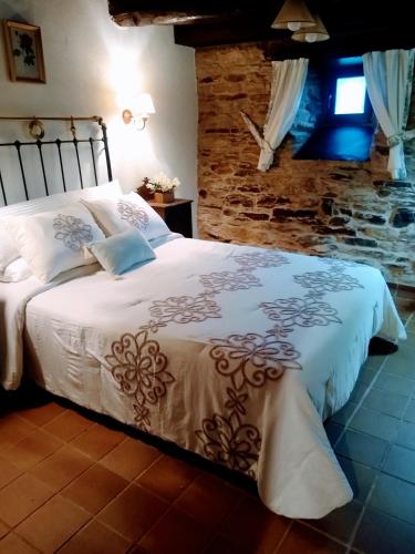 a bedroom with a large bed with a stone wall at Casa Pacios by M de Santiago in Tríacastela