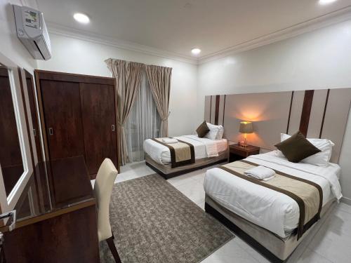 um quarto de hotel com duas camas e uma secretária em ليالي الشرقية لشقق المخدومة em Dammam