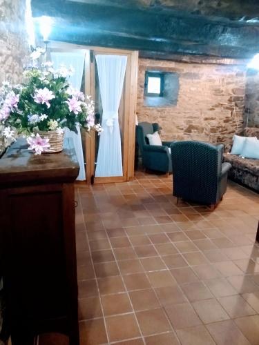 a living room with chairs and flowers on a table at Casa Pacios by M de Santiago in Tríacastela