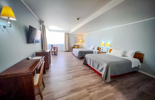 a hotel room with two beds and a desk at Hotel Diego de Almagro Concepción in Concepción