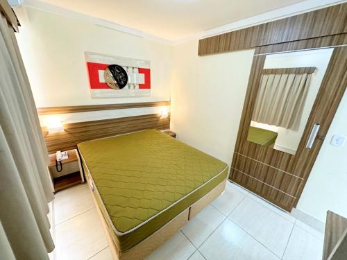 een kleine kamer met een groen bed en een douche bij Lacqua Diroma parque - CN J in Caldas Novas