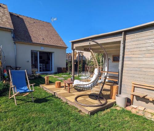 um quintal com um baloiço e uma casa em Le Woody Lodge, Large cottage with wooden deck and chalet with garden view next to Fontainebleau Forest em Achères-la-Forêt