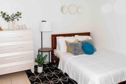 a bedroom with a white bed with pillows and a dresser at NEWLY Renovated condo 5 min from Airport in Miami