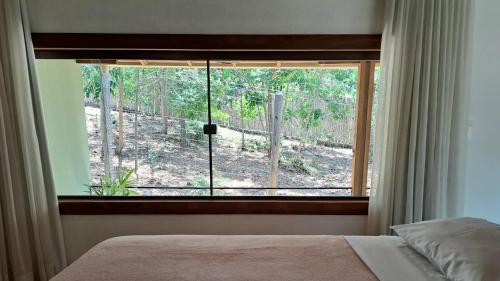 a bedroom with a window with a view of a forest at Chalé Bromélia do Cerrado in Serra do Cipo