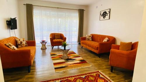 a living room with orange couches and a rug at Nimaro Courts in Entebbe