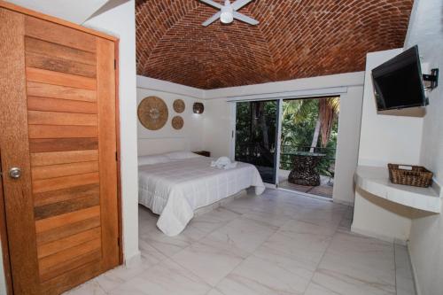 a bedroom with a bed and a tv and a door at Paulas Suites Terraza in Ixtapa