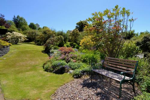 a park bench sitting in the middle of a garden at Lochview House in Fort William