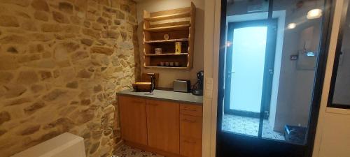 baño con pared de piedra, lavabo y ventana en La grange du Moulin en Érezée