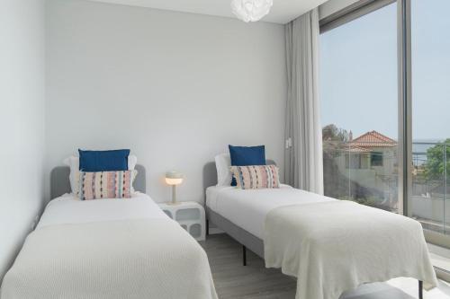 two beds in a room with a large window at Vila Chu by An Island Apart in Ponta do Sol