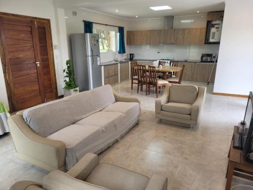 a living room with a couch and chairs and a kitchen at Casa a estrenar en Santa Elena - Santa Clara, Costa Atlantica in Playa Dorada