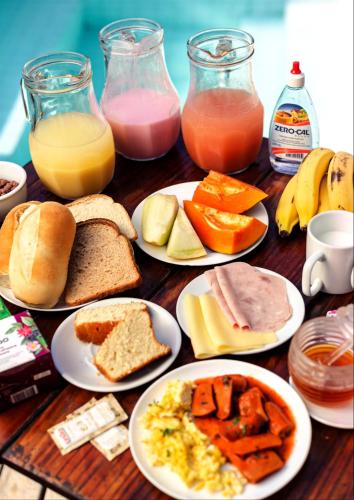 a wooden table with plates of breakfast foods and drinks at Che Lagarto Paraty in Paraty