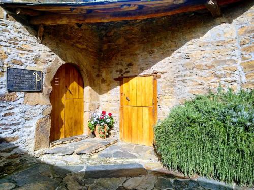 - un bâtiment en pierre avec une porte en bois et des fleurs dans l'établissement Casa Pacios by M de Santiago, à Tríacastela