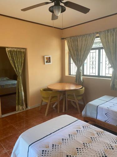 Un dormitorio con 2 camas y una mesa con ventilador de techo. en La Rosa Buga, en Buga