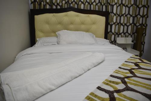 a large white bed with a black and gold headboard at A tastefully furnished one bedroom airbnb apartment along Thika rd, TRM mall in Nairobi