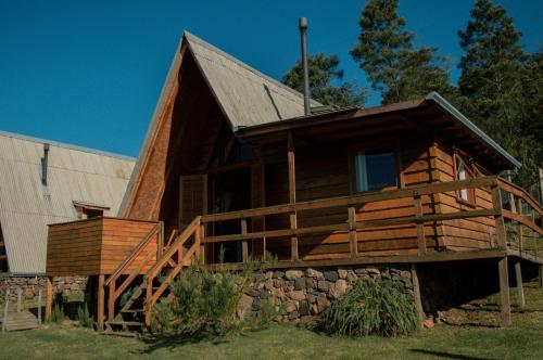 a large log cabin with a porch and a house at Sítio CRIA - Hospedagem Sustentável & Experiências Rurais in Três Coroas