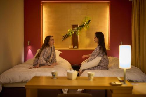 two women sitting on beds in a hotel room at Hotel Resol Trinity Kanazawa in Kanazawa
