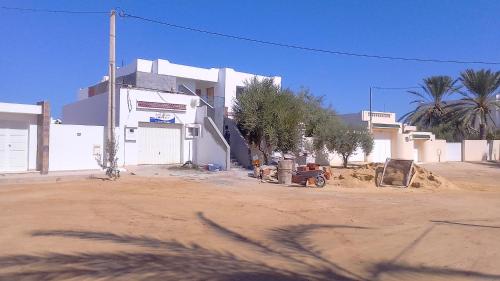 ein weißes Gebäude mit Bäumen und einer unbefestigten Straße in der Unterkunft JRAD in Houmt Souk