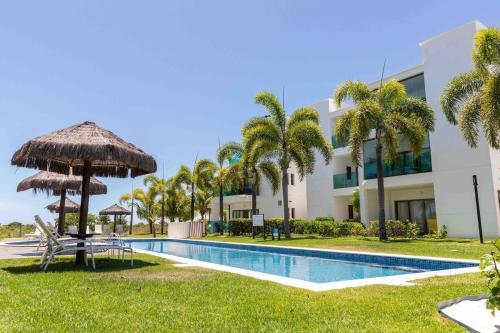 a resort with a swimming pool with a umbrella and palm trees at Complexo Iberostar - Praia do Forte Bahia - Imóveis de Luxo, de 2 e 3 quartos no melhor local da Praia do Forte in Mata de Sao Joao
