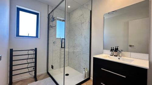 W łazience znajduje się szklana kabina prysznicowa, umywalka i lustro. w obiekcie Manuka Vista w mieście Twizel