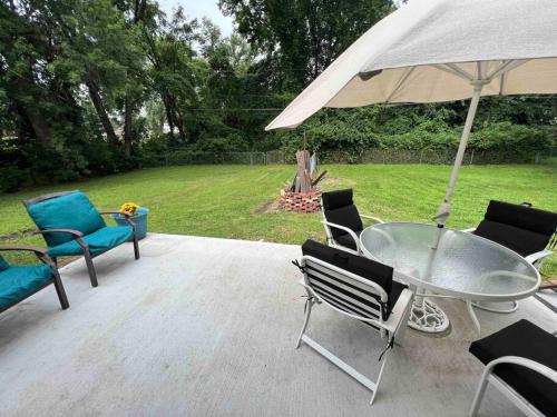 een patio met een tafel en stoelen en een parasol bij Cozy two bedroom home near downtown Shawnee in Shawnee