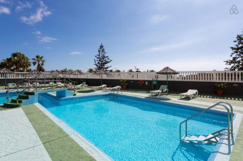 uma grande piscina com cadeiras em Olimpia em Playa de las Americas