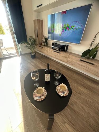 a table with two glasses of wine and a tv at Apartament AntoniaS in Făgăraş