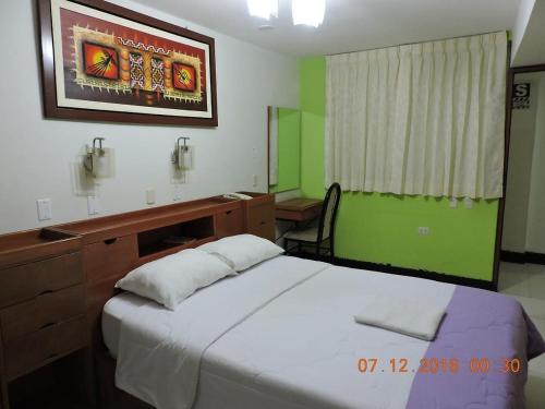 a bedroom with a white bed and a desk and a desk at HOTEL BAYOVAR in Piura