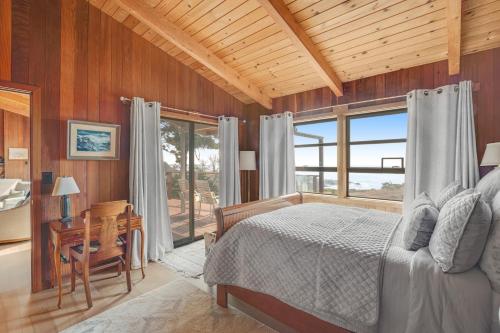 a bedroom with a bed and a desk and windows at Rosemary's Retreat in Mendocino