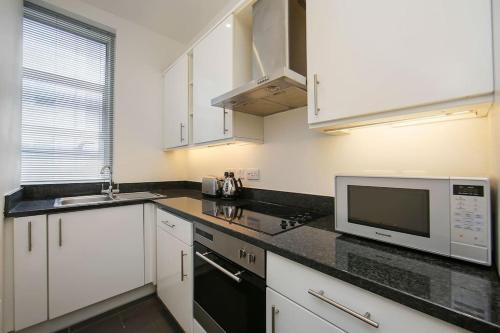 a kitchen with white cabinets and a microwave at 2 Bedroom Apartment-Oxford Street-Central London in London