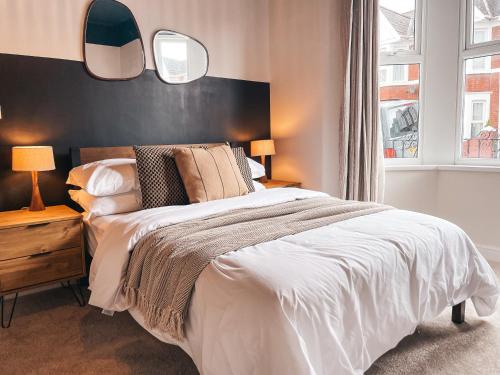 a bedroom with a large bed and two mirrors at Rosslyn House by Solace Stays in Newport