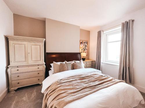 a bedroom with a bed and a dresser and a window at Ty Crindau by Solace Stays (Pool Table) in Newport