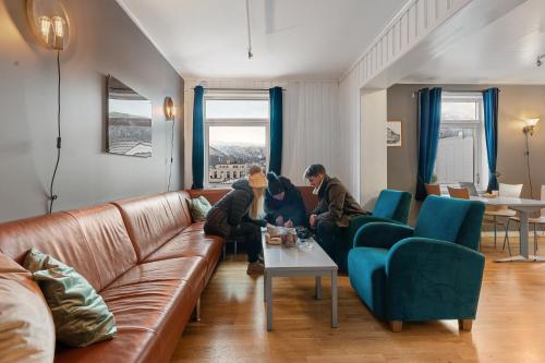 two people sitting on a couch in a living room at Enter Backpack Hotel in Tromsø