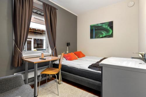 a bedroom with a bed and a desk and a sink at Enter Backpack Hotel in Tromsø