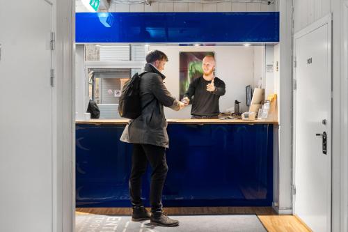 a man shaking another mans hand at a counter at Enter Backpack Hotel in Tromsø