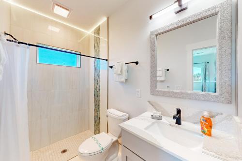 W łazience znajduje się toaleta, umywalka i lustro. w obiekcie Salty Waves 2 w mieście Flagler Beach