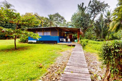 a house in the middle of a field with a wooden walkway at Casa Beluga in Uvita